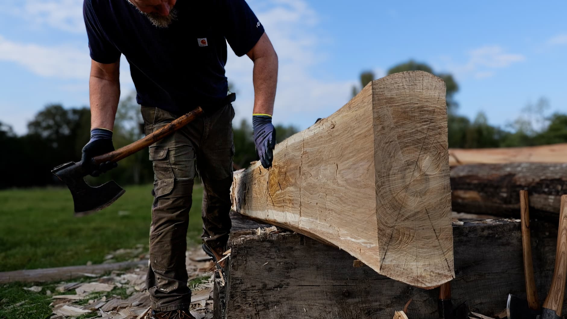 Jesper working with an axe on a timber beam in Latvia